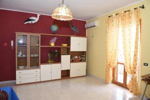 a kitchen with white cabinets and a red wall at SiciliaEtnaMinio in Mascali