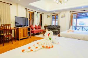 Habitación con 1 dormitorio con 1 cama y TV. en Villa Deux Rivieres双河别墅酒店 en Luang Prabang
