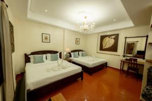 a hotel room with two beds and a chandelier at Villa Deux Rivieres双河别墅酒店 in Luang Prabang