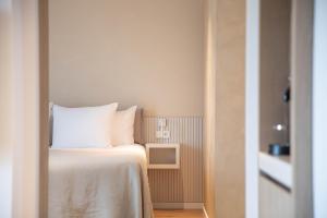 a bedroom with a bed with white sheets and a tv at Hotel Bommelje in Domburg