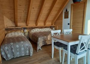 1 dormitorio con 2 camas, mesa y sillas en AL SOGNO en Asiago