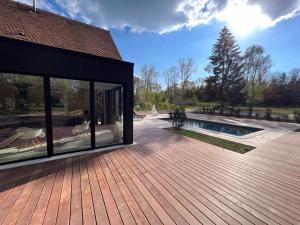 une terrasse en bois avec une piscine et une maison dans l'établissement Domaine Oranga, un design élégant au luxe épuré près des Châteaux de la Loire, à Lanthenay