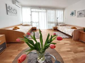 een kamer met 2 bedden en een vaas met bloemen op een tafel bij Apartment Oliva in Knin