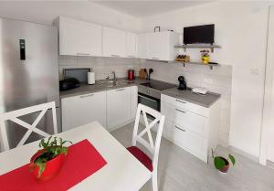 uma cozinha com armários brancos e uma mesa e cadeiras brancas em Apartment Oliva em Knin