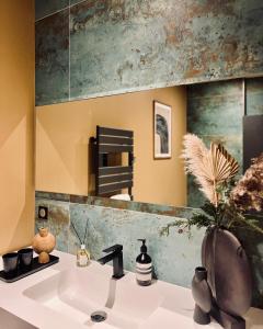 La salle de bains est pourvue d'un lavabo et d'un miroir. dans l'établissement Domaine Oranga, un design élégant au luxe épuré près des Châteaux de la Loire, à Lanthenay