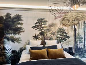- une chambre ornée d'une grande fresque murale d'arbres dans l'établissement Domaine Oranga, un design élégant au luxe épuré près des Châteaux de la Loire, à Lanthenay