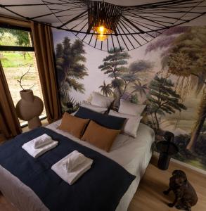 - une chambre avec un grand lit avec un chien assis dans l'établissement Domaine Oranga, un design élégant au luxe épuré près des Châteaux de la Loire, à Lanthenay
