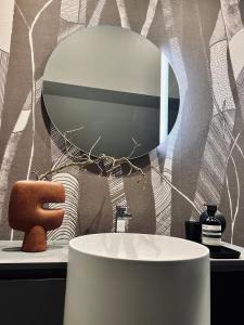 La salle de bains est pourvue d'un miroir rond et d'un lavabo. dans l'établissement Domaine Oranga, un design élégant au luxe épuré près des Châteaux de la Loire, à Lanthenay