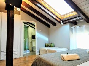 1 dormitorio con 2 camas y baño con tragaluz. en Casa Rural Madera y Sal, en Salinas de Añana
