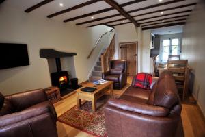 a living room with leather furniture and a fireplace at No 3 The Forge Coniston in Coniston