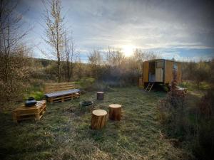 a tent and benches in a field with the sun at Maringotka Za Trnkou 