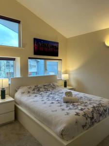 a bedroom with a bed with two lamps and two windows at Cosy House near city centre and football stadium in Manchester