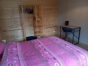 ein rosa Bett in einem Zimmer mit einem Schreibtisch in der Unterkunft La fermette - chambres d'hôtes dans environnement calme et arboré in Saint-Jean-des-Baisants