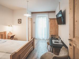 a bedroom with a bed and a desk with a television at Hotel Turmwies in Tirolo