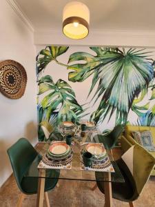Cozy Apartment in central Almada w Swing Chairs في ألمادا: طاولة طعام مع كراسي و لوحة لأشجار النخيل