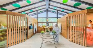 a woman standing in a room with wooden walls at Alpin & Wellness Resort Ludwig Royal in Oberstaufen