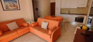 sala de estar con sofá naranja y cocina en La Casa di Lisa 2, en Valledoria