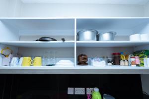 a kitchen shelf filled with dishes and other kitchen items at The Bliss - Lovely 1 bedroom apartment located near TRM mall in Nairobi