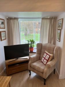 a living room with a chair and a flat screen tv at Luxury Super King Bed - Private Flower Garden in Stratford-upon-Avon
