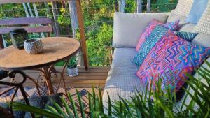 a couch on a porch with pillows and a table at Deluxe Studio with Forest Views, Noosa Hinterland in Doonan