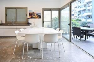 a white dining room with a white table and chairs at Mamma Mia by HolyGuest in Tel Aviv