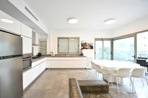 a large white kitchen with a table and chairs at Mamma Mia by HolyGuest in Tel Aviv