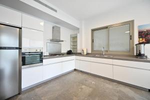 a kitchen with white cabinets and a stainless steel refrigerator at Mamma Mia by HolyGuest in Tel Aviv