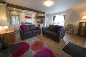 a living room with two couches and a kitchen at Poppy Cottage, lake view holiday cottage in Coniston in Coniston
