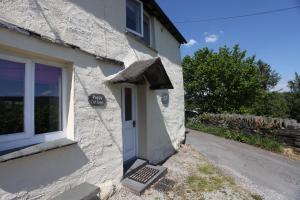 a white building with a door and a window at Poppy Cottage, lake view holiday cottage in Coniston in Coniston