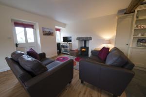 a living room with two leather couches and a fireplace at Poppy Cottage, lake view holiday cottage in Coniston in Coniston