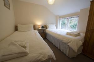 two beds in a room with a window at Poppy Cottage, lake view holiday cottage in Coniston in Coniston