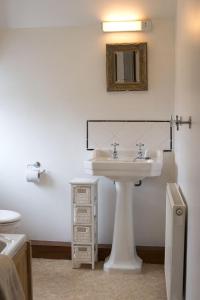 a white bathroom with a sink and a mirror at Poppy Cottage, lake view holiday cottage in Coniston in Coniston +11 photos