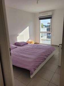 ein Schlafzimmer mit einem Bett mit violetter Bettwäsche und einem Fenster in der Unterkunft Superbes appartements neufs à Montpellier in Montpellier