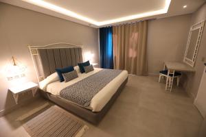 a bedroom with a large bed with blue pillows at Suites Hôtel Les Charmilles & Spa in La Marsa