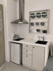 una cocina con armarios blancos, fregadero y vajilla en Allegro suite en Tinos Town