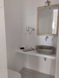 y baño con lavabo de piedra y espejo. en Allegro suite en Tinos Town