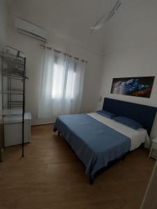 een slaapkamer met een blauw bed in een witte kamer bij Struttura Le Gemme in Marettimo