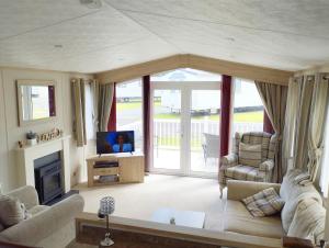 a living room with a couch and a tv at Sand Le Mere Holiday Village Caravan hire in Tunstall