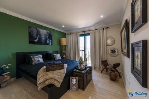 een woonkamer met een blauw bed en groene muren bij Villa Monte Leon in Maspalomas