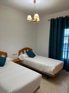 1 dormitorio con 2 camas y cortina azul en VILLA LA MOMITA, en Chiclana de la Frontera