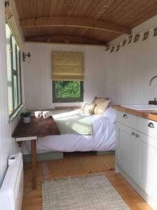 a small bedroom with a bed and a window at The Warren - Cosy Shepherds Hut in beautiful wild meadow in Halesworth
