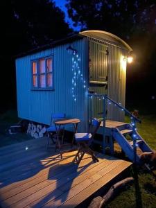 a tiny house with two chairs and a table on a deck at The Warren - Cosy Shepherds Hut in beautiful wild meadow in Halesworth