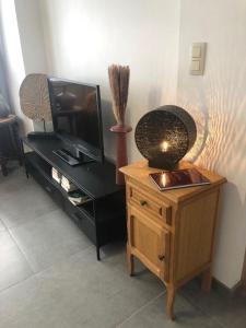 - un salon avec une télévision et une commode en bois dans l'établissement L'Escapade Urbaine - Montignies-sur-Sambre, à Charleroi