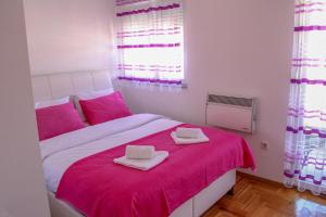 - une chambre avec un lit rose et 2 serviettes dans l'établissement Lanai Apartment, à Trebinje