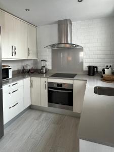 uma cozinha com armários brancos e um forno com placa de fogão em TarifaMiCasa Mar Tirreno em Tarifa