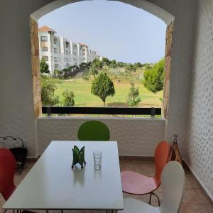 a table and chairs in a room with a large window at Asilah Marina Golf, Appartement au calme in Asilah