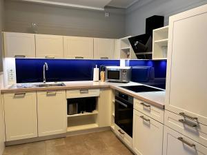 una cocina con armarios blancos y una pared azul en Prora Strand Appartement en Binz