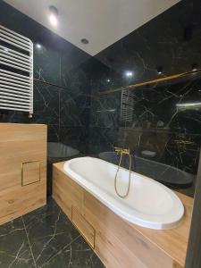 a bathroom with a white tub and a black wall at Apartament Dubaj in Gliwice