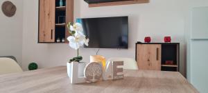 a room with a table with a tv and a vase with flowers at LuengiHouse - Espectacular apartamento con piscina in Lloret de Mar