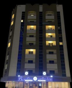 アジュマーンにあるNew Royal Palace Hotel Apartmentsの青い看板が目の前にある高い建物